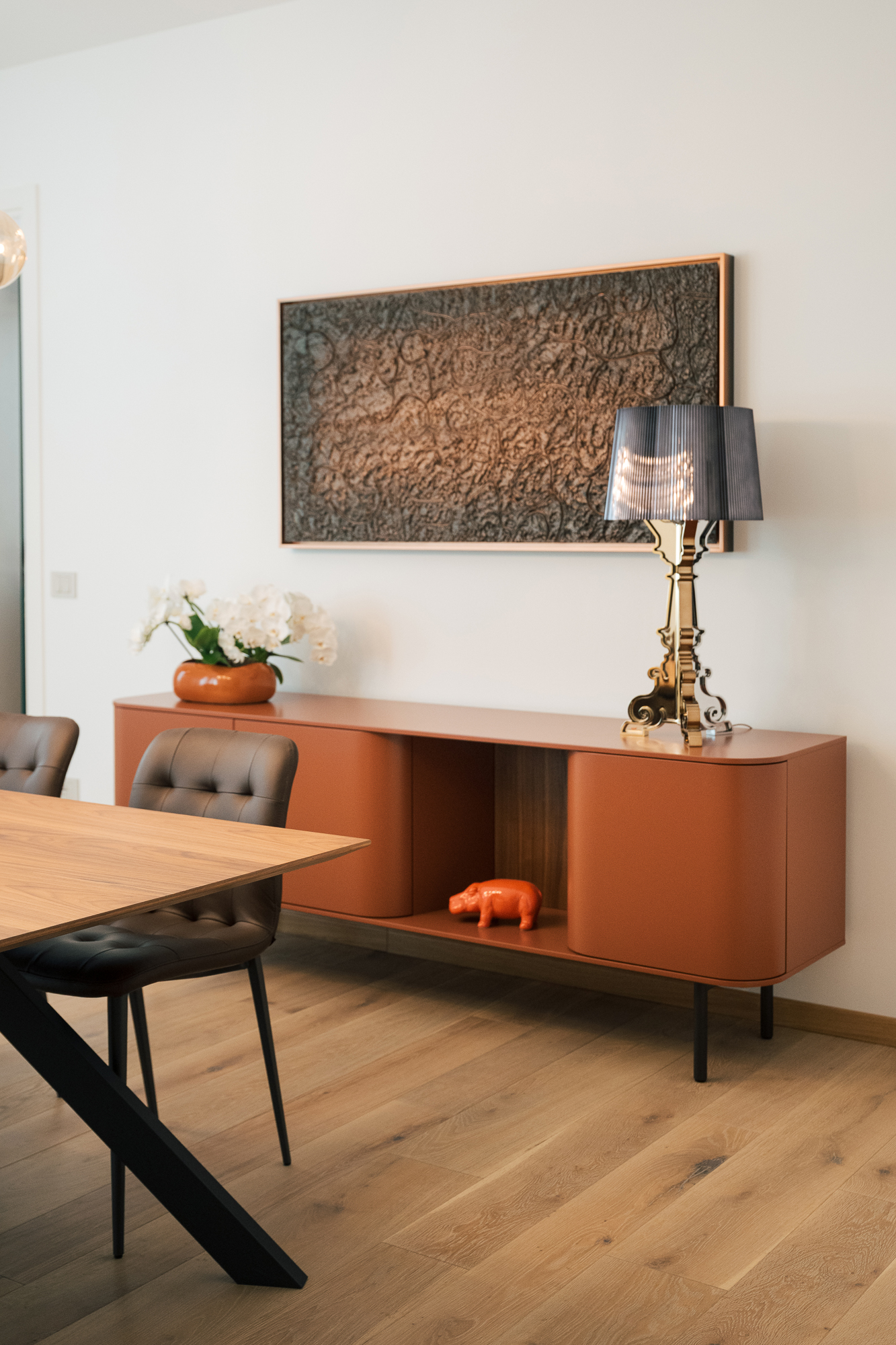 Dettaglio della sala riunioni con madia colorata, lampada decorativa e tavolo in legno