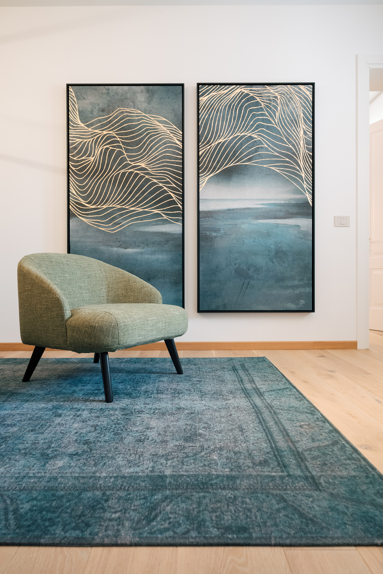 Area attesa dell’ufficio con poltrona verde, tappeto blu e quadri decorativi