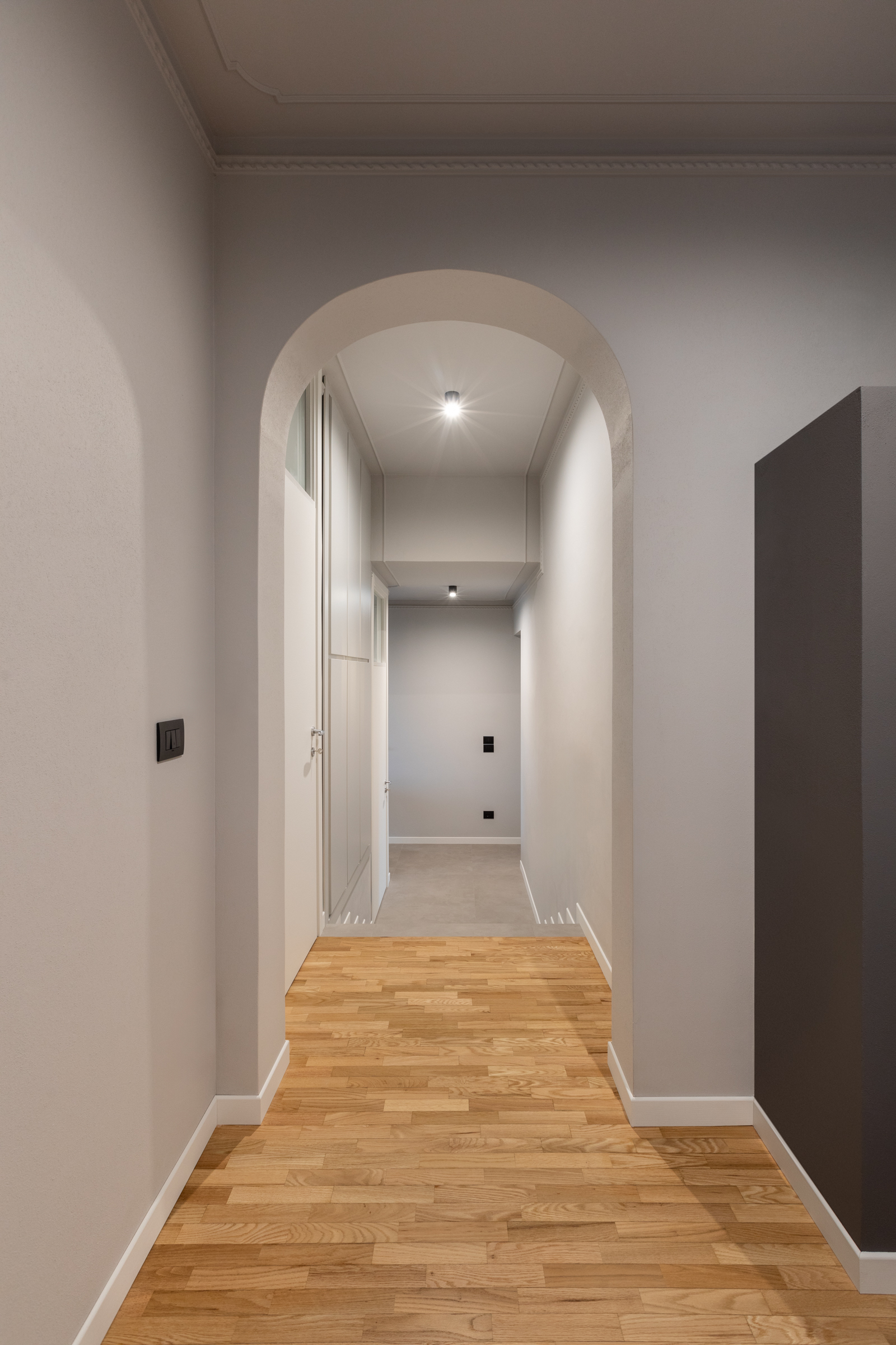 Corridoio con arco e pavimento in legno nella ristrutturazione di casa anni Sessanta