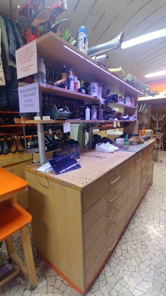 Zona di lavoro prima dell’intervento con banco operativo, scaffali e prodotti in lavorazione