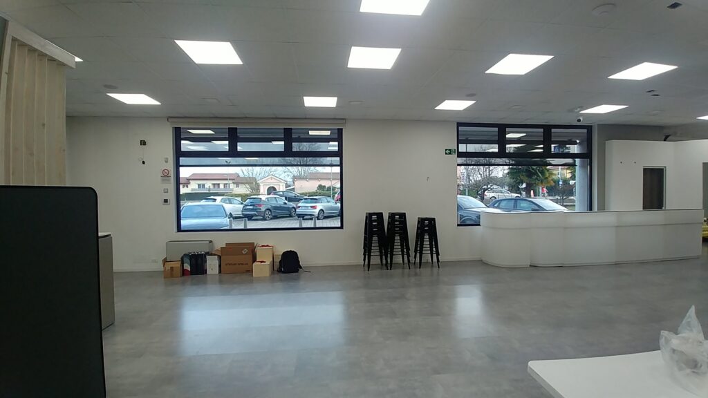 Spazio esistente prima del progetto con ambiente ampio, illuminazione tecnica, arredi minimi e assenza di una funzione rappresentativa definita
