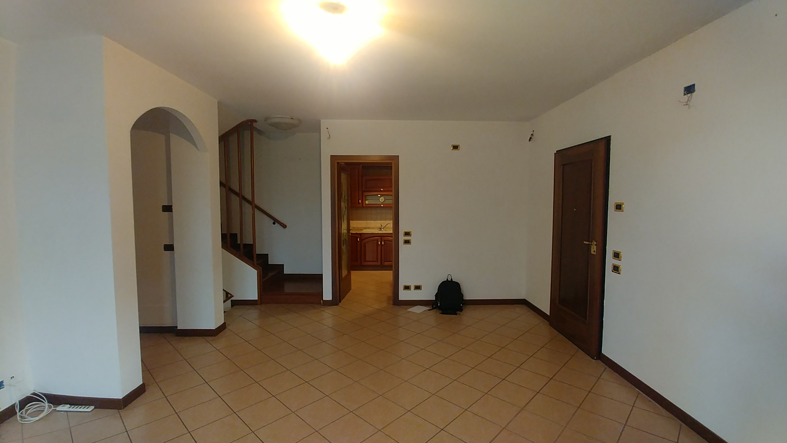 Zona giorno prima dell’intervento con pavimento scuro, arredi datati e spazi poco luminosi
