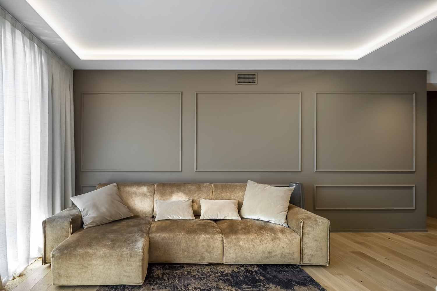 Appartamento C, soggiorno con divano beige, boiserie classica e illuminazione indiretta a soffitto