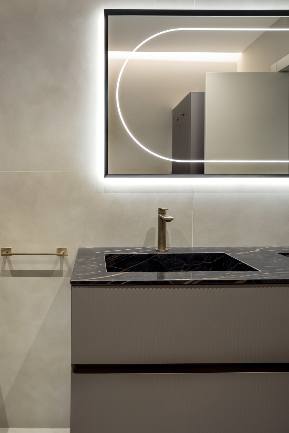 Appartamento C, dettaglio del lavabo con piano nero effetto marmo Noir Désir e specchio retroilluminato