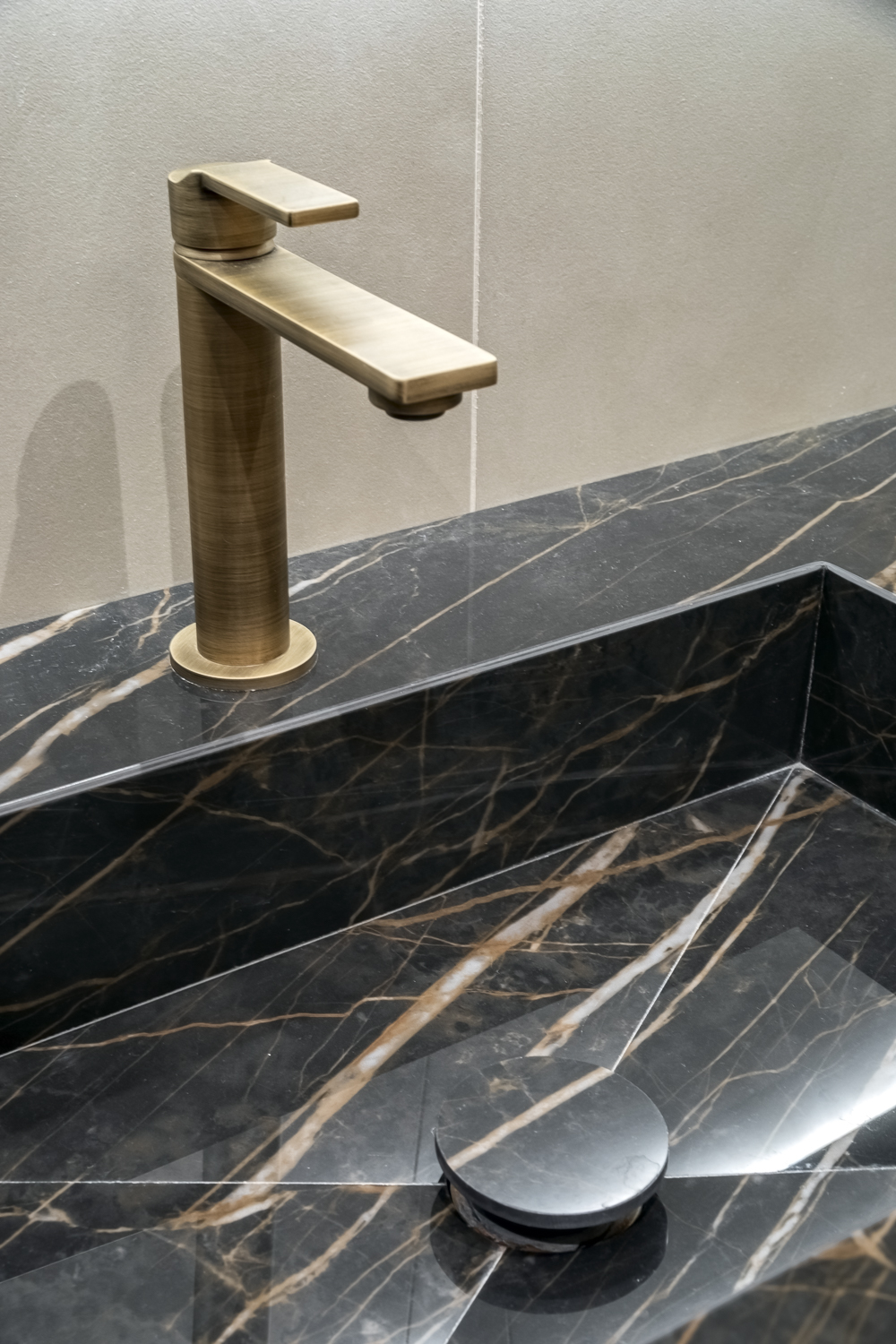 Appartamento C, dettaglio del lavabo in effetto marmo Noir Désir con rubinetteria in finitura bronzo