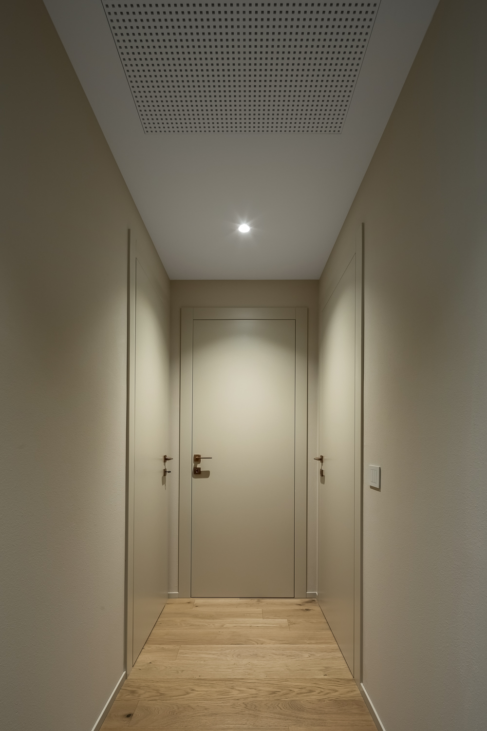 Appartamento C, corridoio con boiserie chiara, pavimento in legno e illuminazione integrata a soffitto