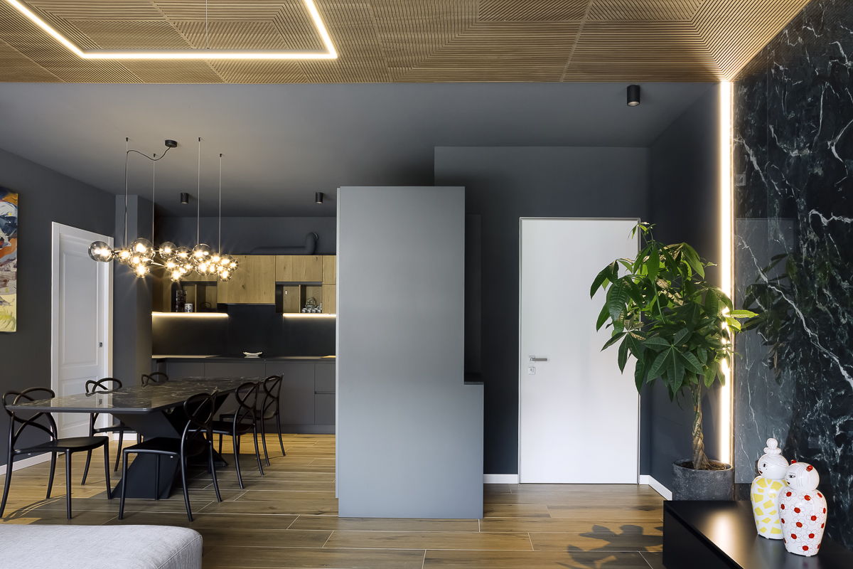 Appartamento YL, vista della zona pranzo e cucina con pareti grigio scuro, soffitto in noce canaletto e illuminazione integrata