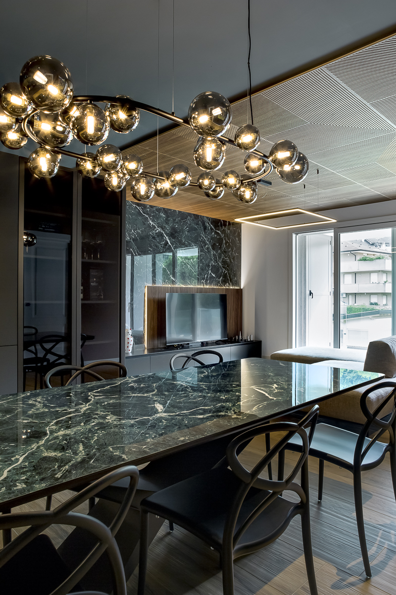 Appartamento YL, zona pranzo con tavolo in marmo verde, lampada decorativa e vista verso il soggiorno