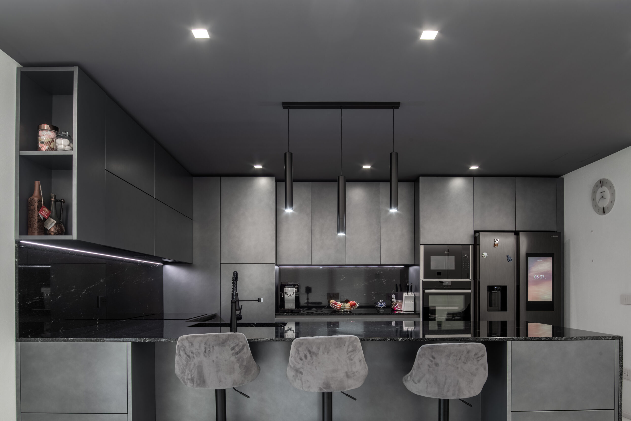 Cucina con finitura metallizzata scura e penisola con sgabelli