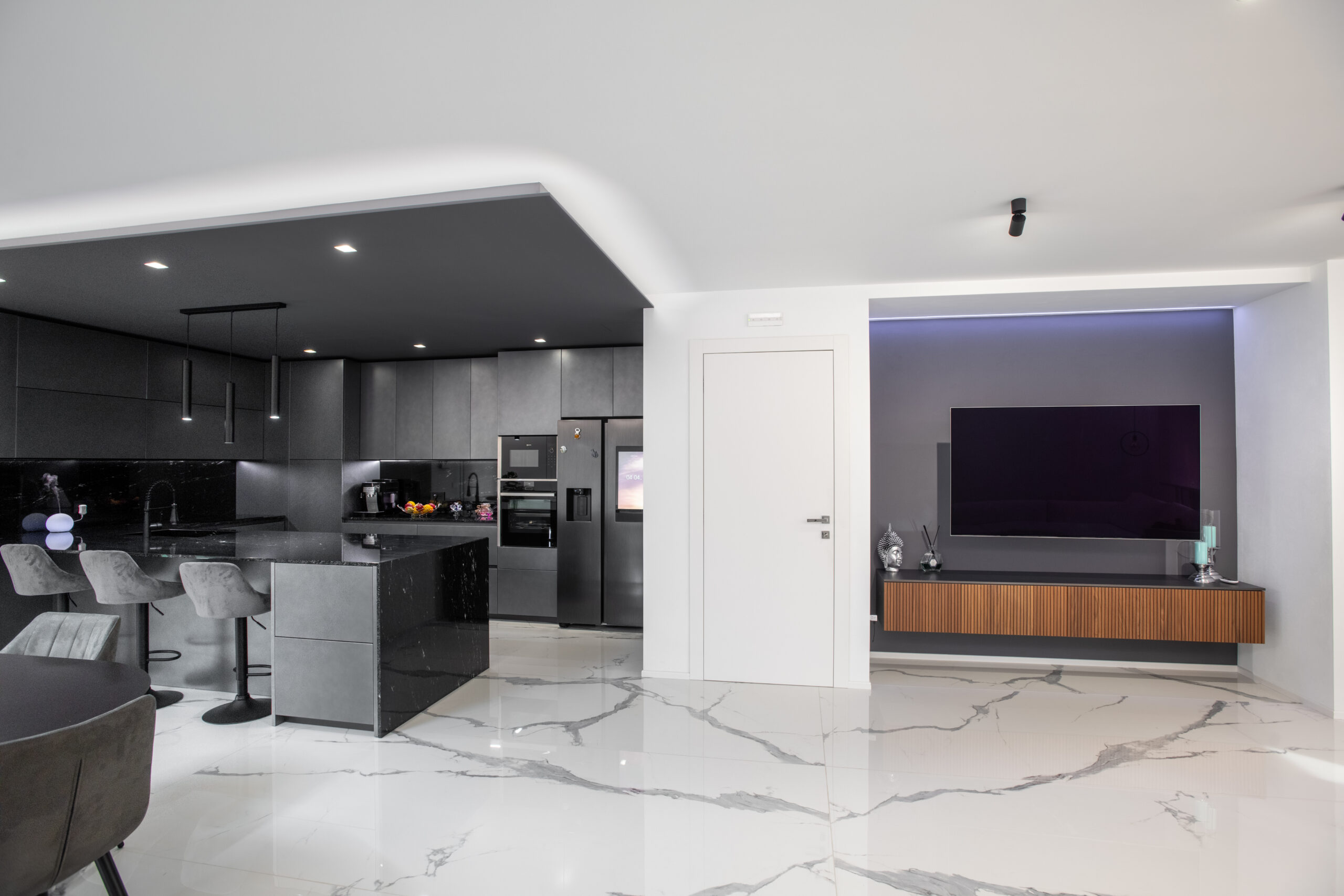 Zona giorno con cucina scura, parete TV e pavimento effetto marmo