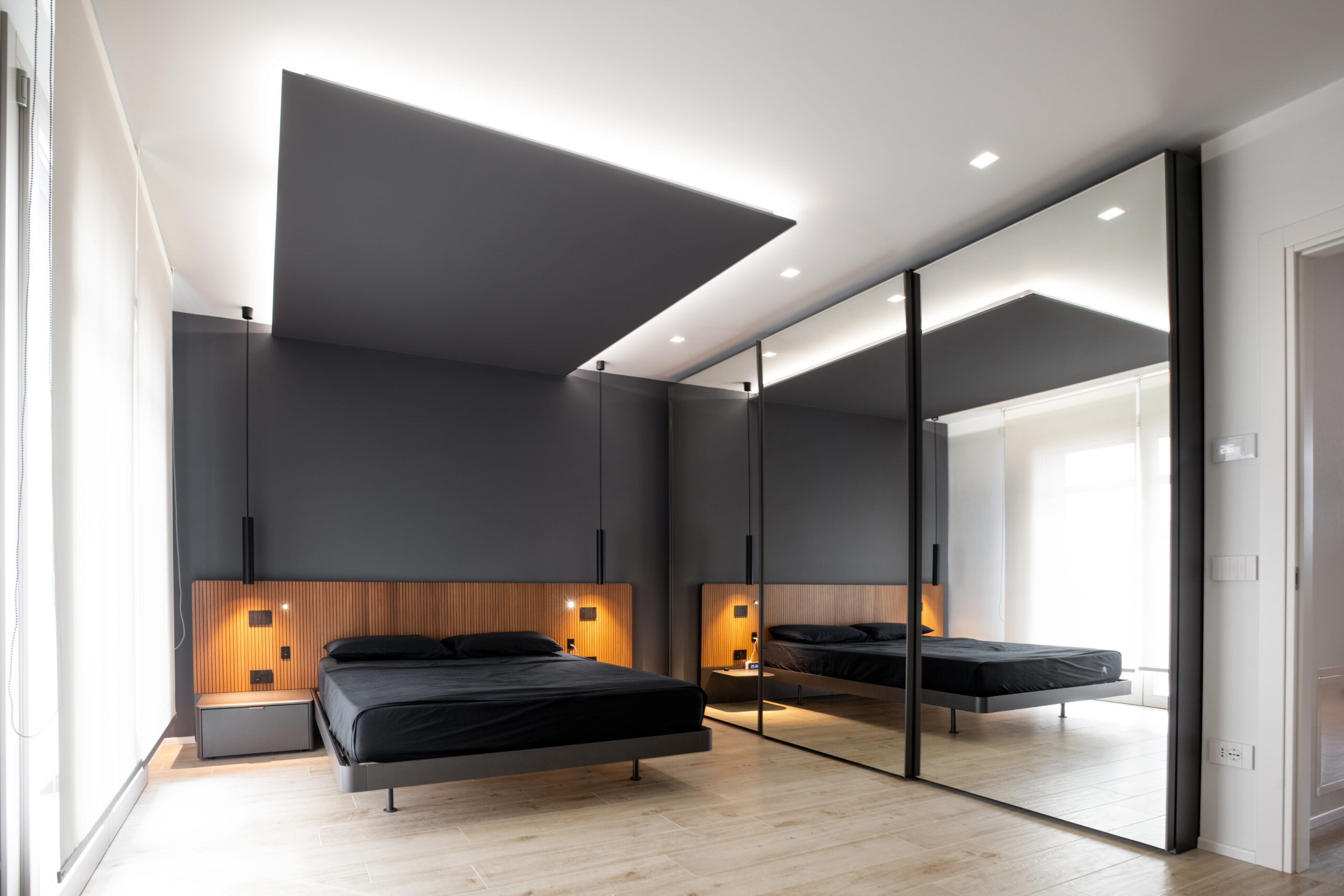 Camera da letto contemporanea con parete scura, boiserie in legno e armadio a specchio
