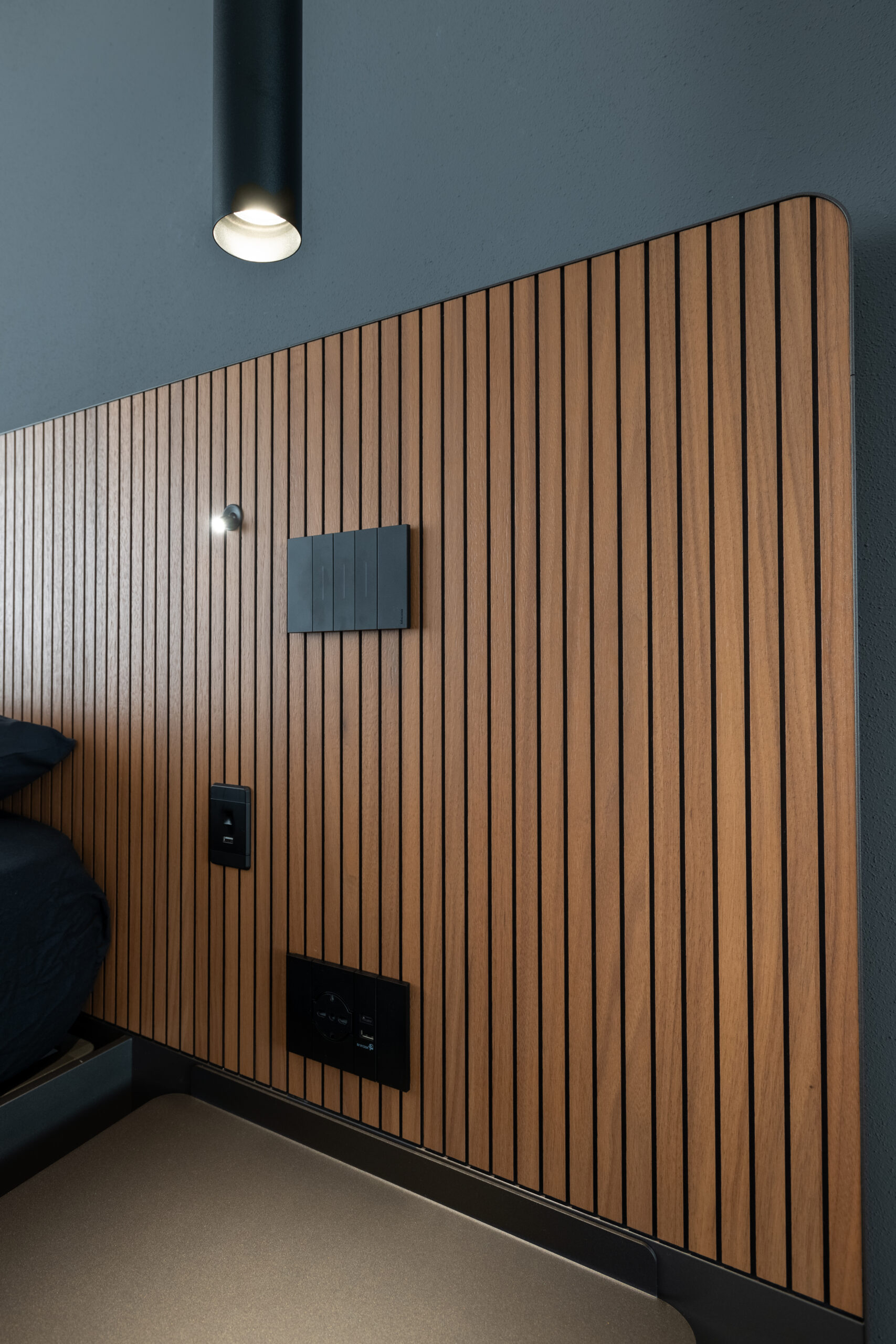 Dettaglio della boiserie in legno con illuminazione integrata nella camera matrimoniale