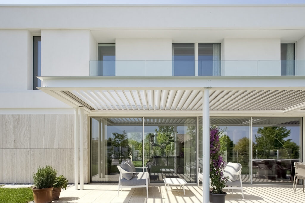 Casa P, pergola bianca e grandi vetrate della zona giorno affacciata sul giardino