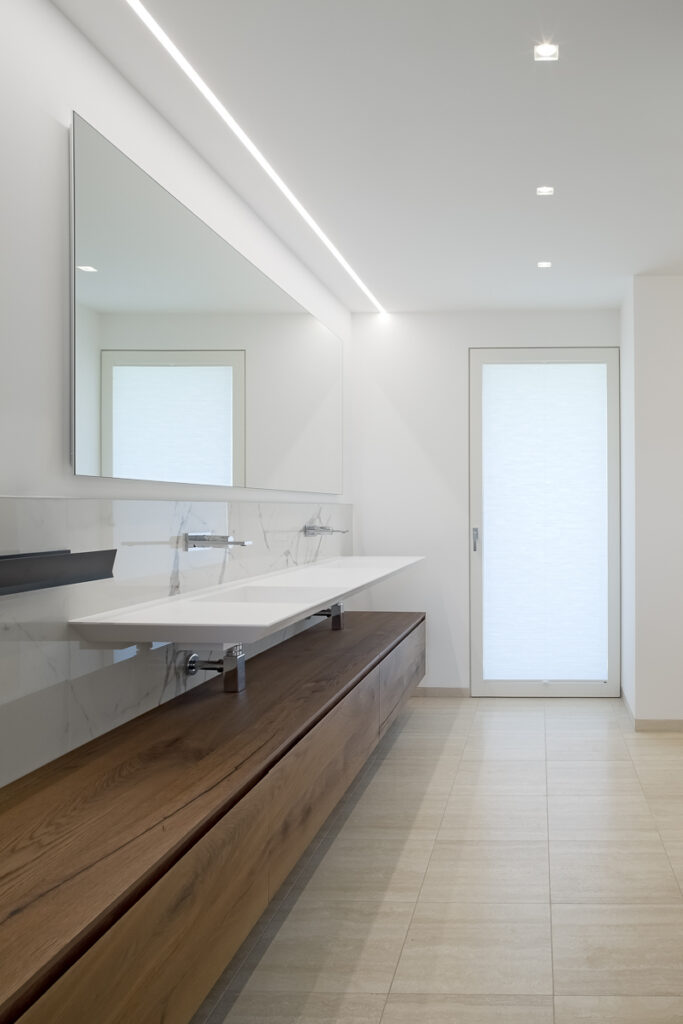 Casa P, bagno contemporaneo con mobile lavabo in legno, doppio lavabo e illuminazione integrata