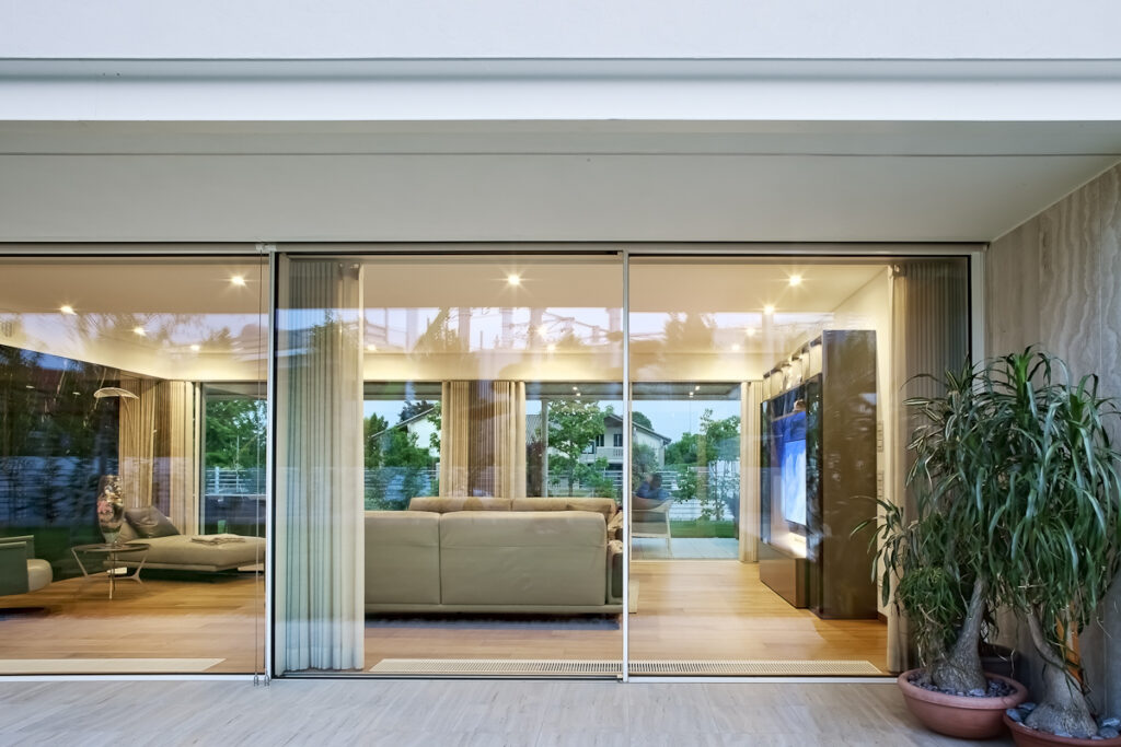 Casa P, zona giorno aperta sul giardino attraverso grandi vetrate e portico