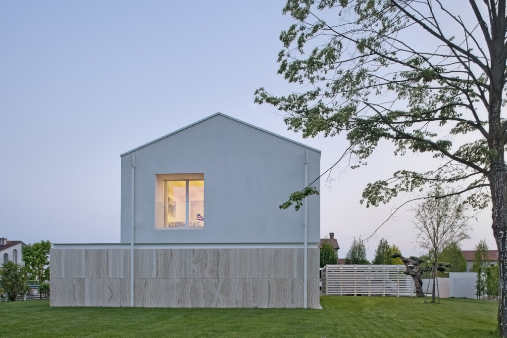 Casa P, prospetto laterale della villa contemporanea con rivestimento in travertino