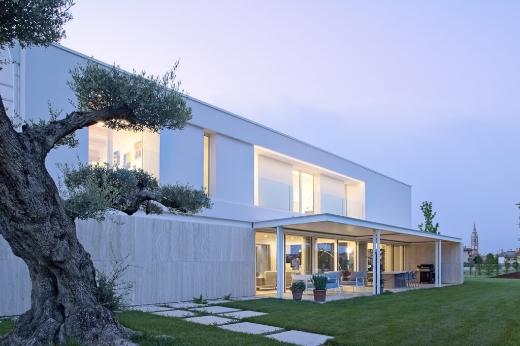 Villa contemporanea con grandi vetrate e ulivo in primo piano